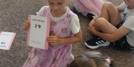 Powiększ grafikę: Dziewczynka w różowej sukience z Pushennem trzyma kartkę z datą swoich urodzin - 29 listopada