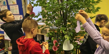 Powiększ grafikę: Dzieci zawieszają swoje serca walentynkowe na drzewie.