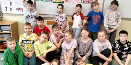 Powiększ grafikę: 8.	Uśmiechnięte dzieci trzymają plakat z napisem wiosna, kwiatami, motylami i słońcem.