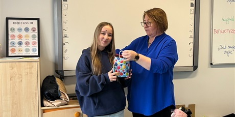 Powiększ grafikę: Nauczycielka obdarowuje uczennicę nagrodą za konkurs literacki. Uczennica jest bardzo szczęśliwa i dumna ze swojej pracy.