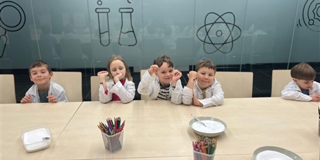 Powiększ grafikę: Piątka uśmiechniętych dzieci siedzi przy stole. Czekają na dalszą część spotkania z bursztynem.