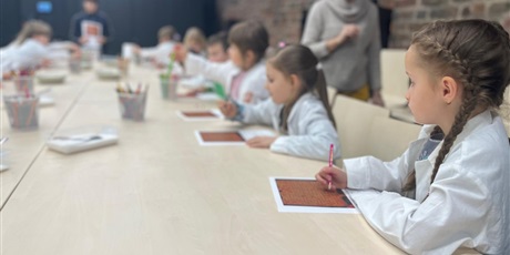 Powiększ grafikę: Dzieci wykonują zadanie. Mają przed sobą kartki z treścią a ręku pisaki.