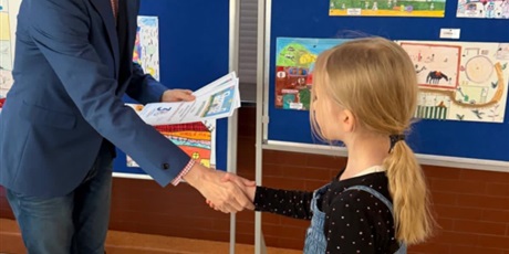 Powiększ grafikę: Dziewczynka odbiera dyplom od dyrektora szkoły za udział w konkursie "Szkoła moich marzeń".