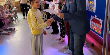 Powiększ grafikę: Dziewczynka odbiera dyplom od dyrektora szkoły za udział w konkursie "Szkoła moich marzeń".